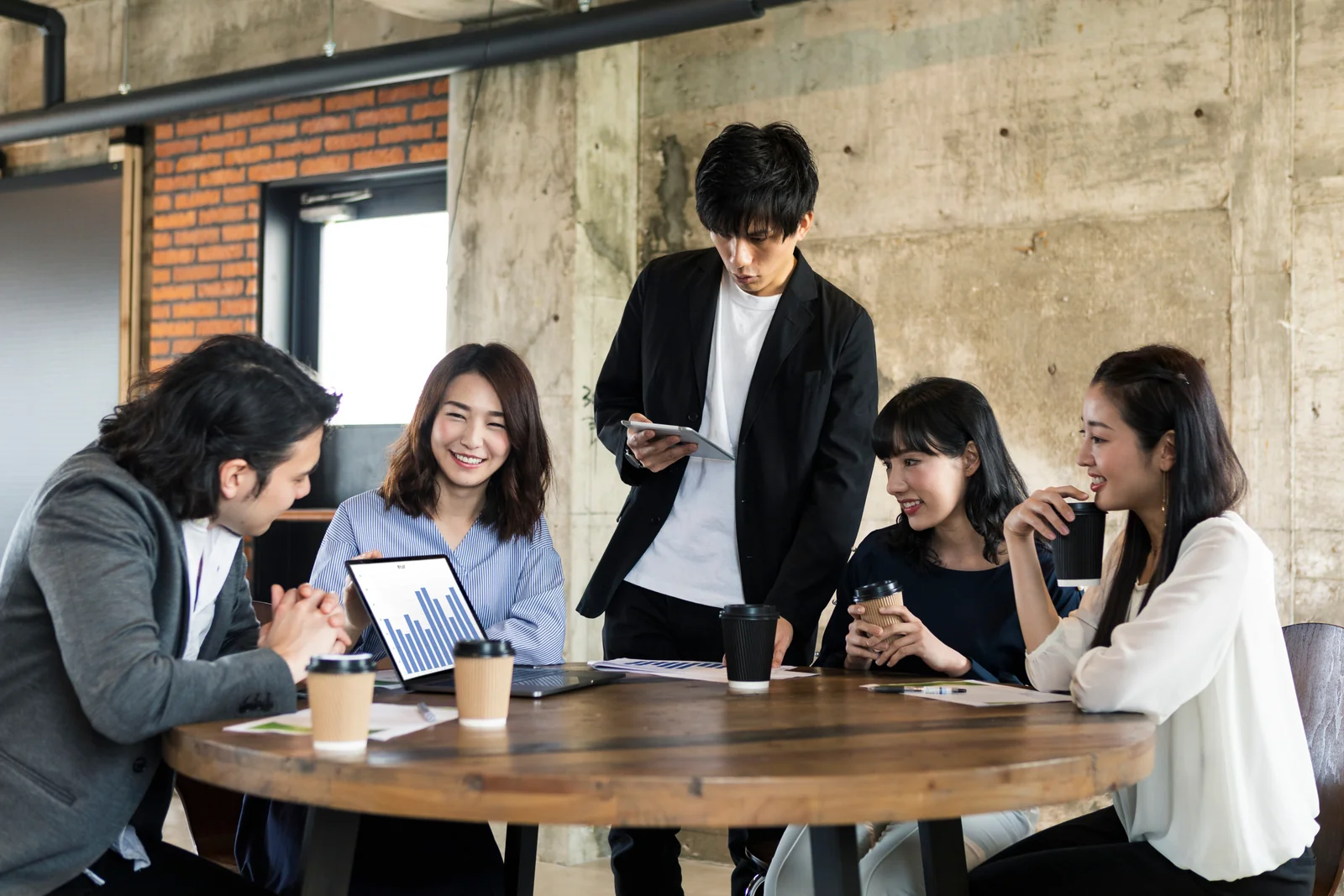 資料とパソコンを囲み、Webサイトの企画を相談するイメージ